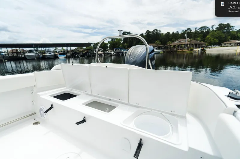 Slide: The Image of 2025 Sea Hunt Ultra 229 boat interior with open storage compartments, docked by a serene lake. - 24