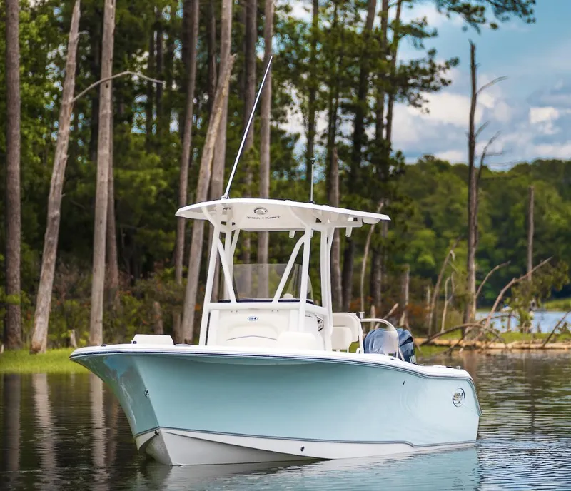 Slide: The Image of 2025 Sea Hunt Ultra 229 boat on a serene lake with forest backdrop. - 3