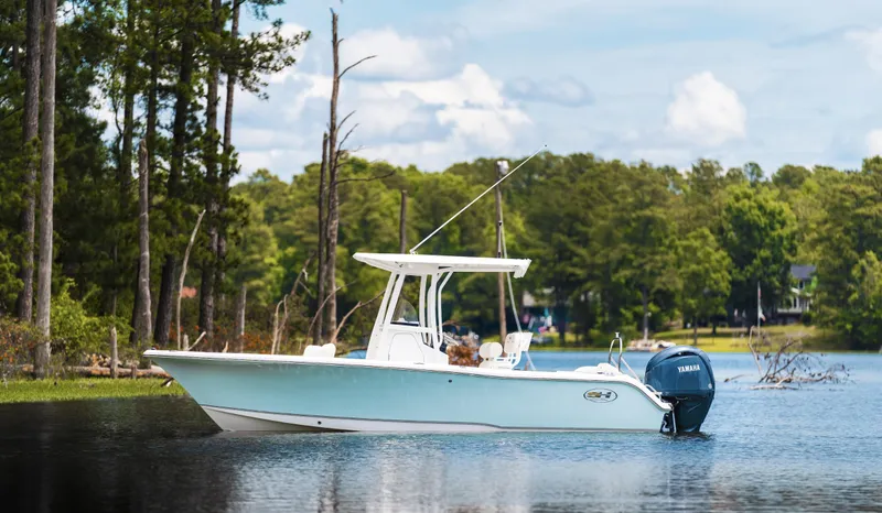 Slide: The Image of 2025 Sea Hunt Ultra 229 boat on a serene lake with lush green trees. - 6