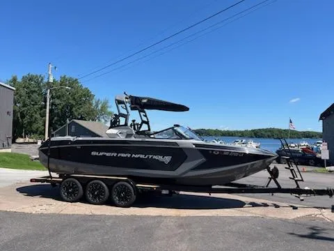 Slide: The Image of 2019 Correct Craft Nautique G 25 Super Air boat on trailer by a lake. - 1