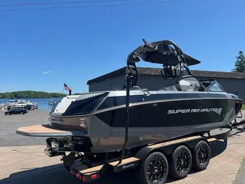 Slide: The Image of 2019 Correct Craft Nautique G 25 Super Air boat on trailer by a lake. - 2