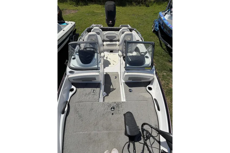 Slide: The Image of 2018 Nitro Z19 Sport boat interior with seating and open windshield, parked on grass. - 5