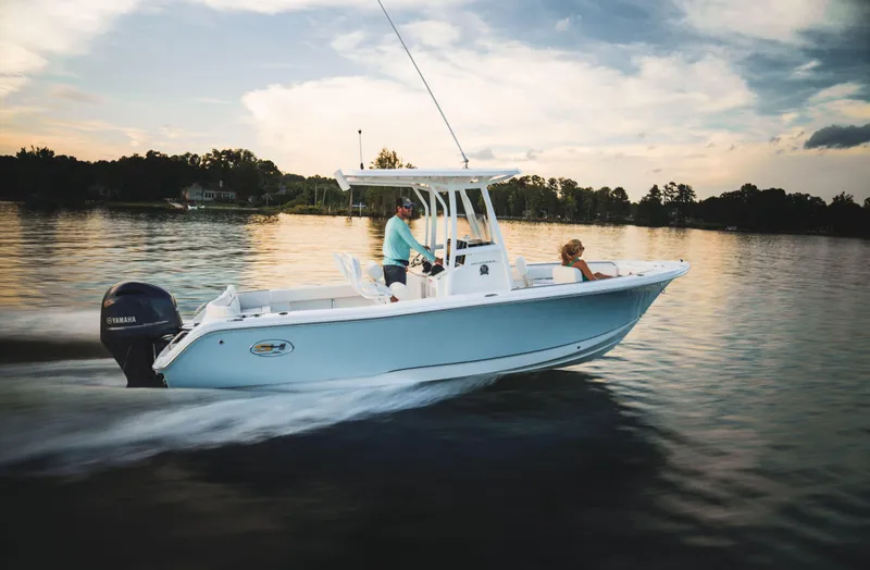 Slide: The Image of 2024 Sea Hunt Ultra 234 boat cruising on a calm lake at sunset. - 1
