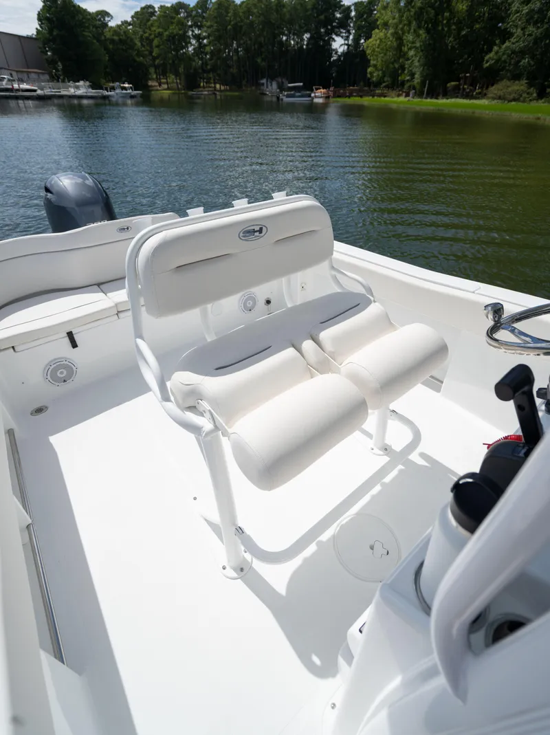 Slide: The Image of 2024 Sea Hunt Ultra 234 boat interior with cushioned seating on a calm lake. - 16