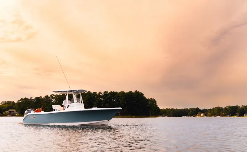 Slide: The Image of 2024 Sea Hunt Ultra 234 boat cruising on a lake at sunset. - 27