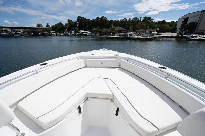 Slide: The Image of 2024 Sea Hunt Ultra 234 boat bow seating area on a calm lake. - 9
