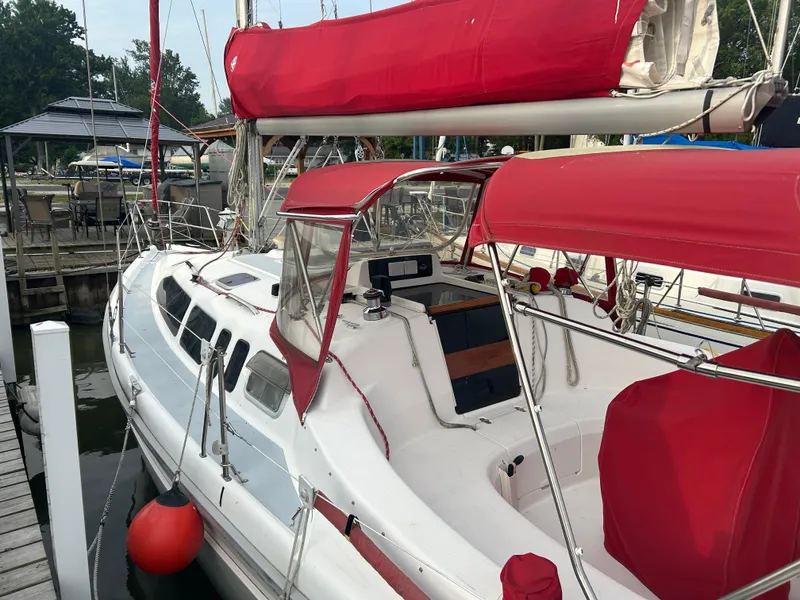 Slide: The Image of Sailboat Hunter 336, 1996 model, with red sails and canopy docked at marina. - 10