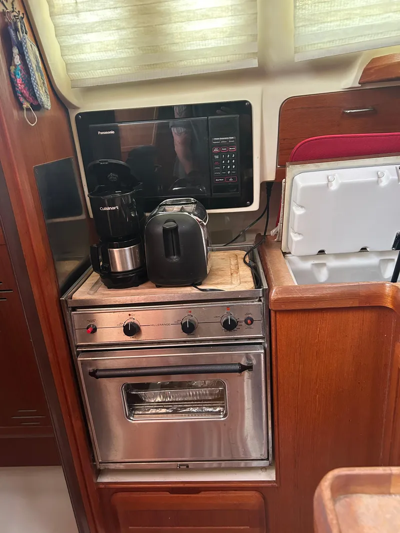 Slide: The Image of Compact kitchen in a 1996 Hunter 336 sailboat with appliances and wooden cabinetry. - 27