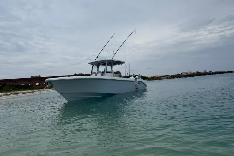 Slide: The Image of 2024 Everglades 315 Center Console boat anchored in calm waters near a shoreline. - 18