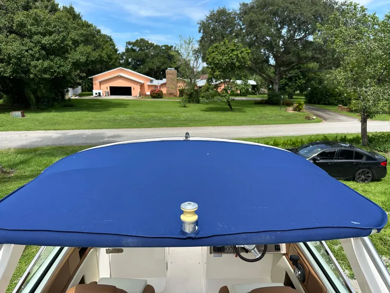 Slide: The Image of 2012 Sea Ray SLX 270 boat with blue canopy, parked in a residential area. - 12