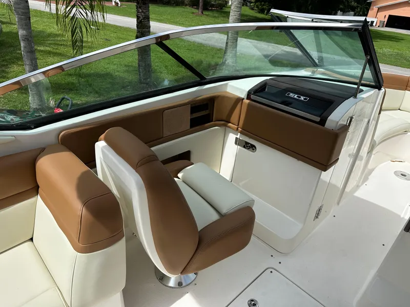 Slide: The Image of 2012 Sea Ray SLX 270 boat interior with tan and white seating, near palm trees. - 14