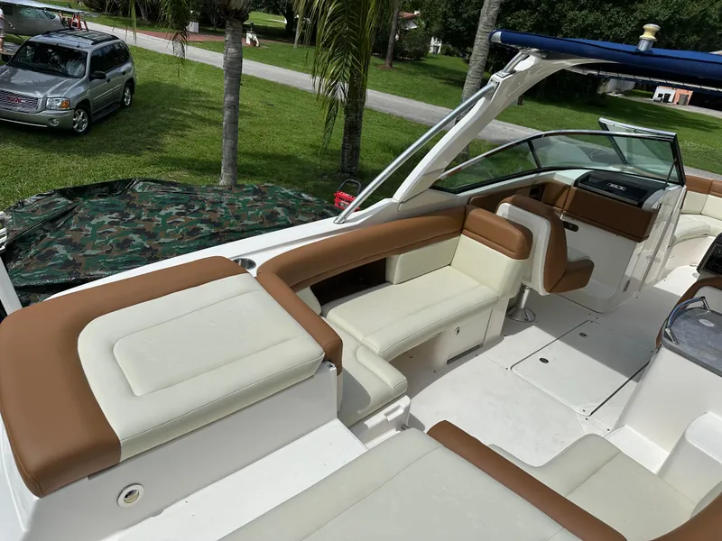 Slide: The Image of 2012 Sea Ray SLX 270 boat interior with tan and white seating, parked outdoors. - 16