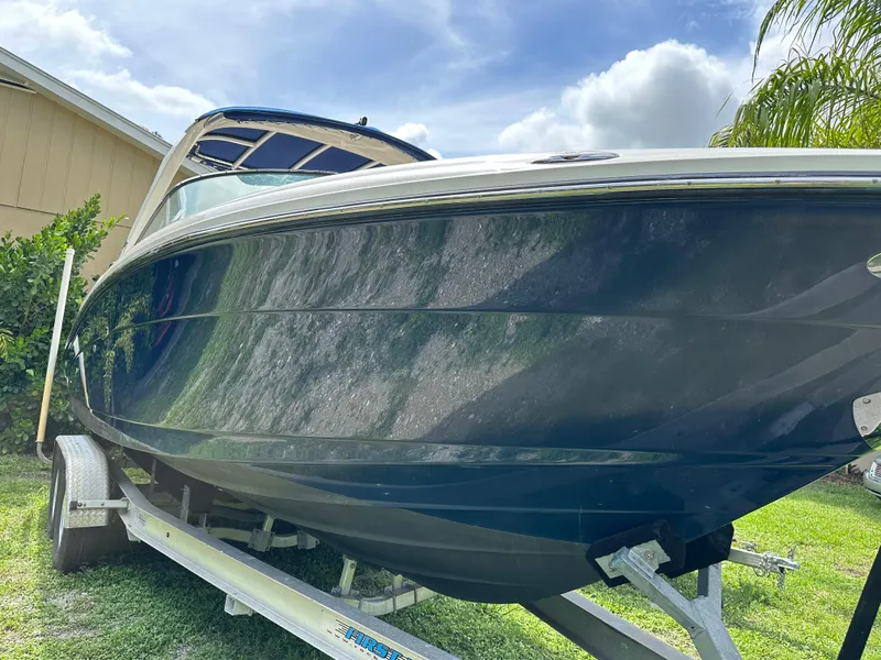 Slide: The Image of 2012 Sea Ray SLX 270 boat on trailer, parked on grass under a blue sky. - 18