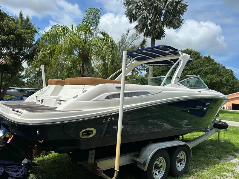 Slide: The Image of 2012 Sea Ray SLX 270 boat on trailer, surrounded by lush palm trees. - 19