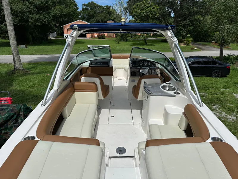 Slide: The Image of 2012 Sea Ray SLX 270 boat interior with tan and white seating, parked on grass. - 3