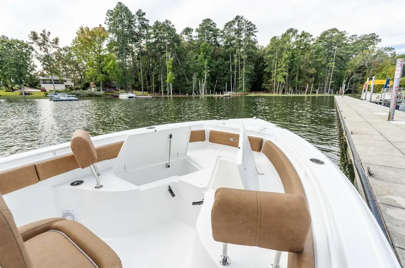 Slide: The Image of 2025 Sea Hunt Ultra 235 SE boat on a serene lake with lush trees. - 13