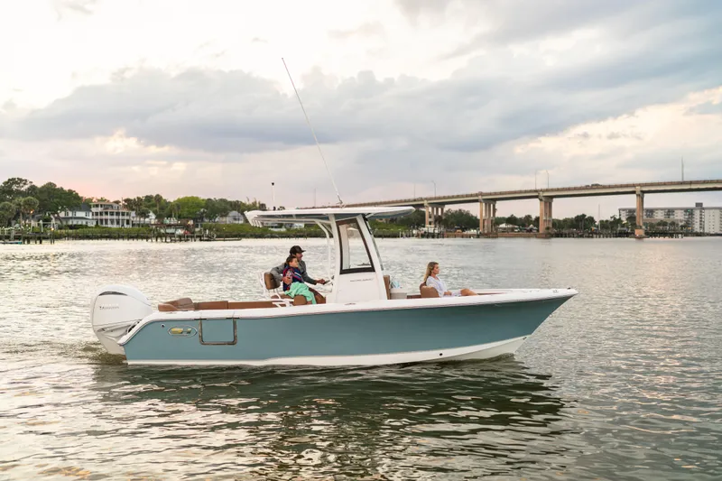 Slide: The Image of 2026 Sea Hunt Ultra 235 SE boat cruising on a calm river near a bridge. - 2