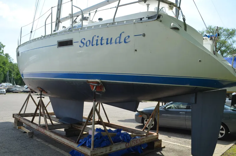 Slide: The Image of 1993 Beneteau Oceanis 370 sailboat named "Solitude" on a trailer in a parking lot. - 1
