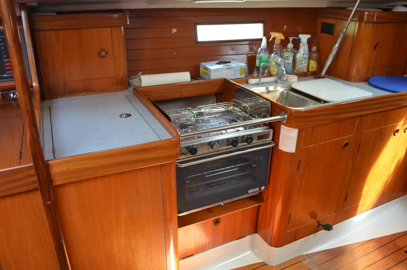 Slide: The Image of 1993 Beneteau Oceanis 370 yacht kitchen with stove, sink, and wooden cabinetry. - 16