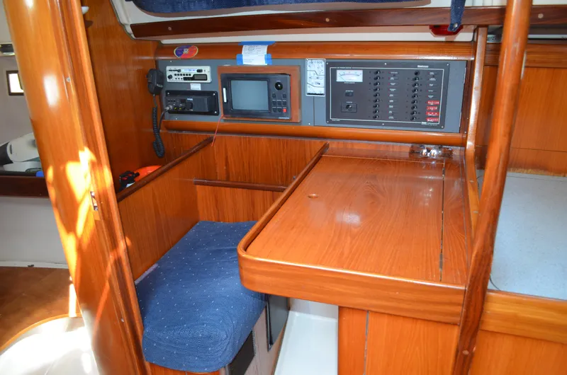 Slide: The Image of Navigation station inside a 1993 Beneteau Oceanis 370 sailboat, featuring wooden cabinetry and control panels. - 9