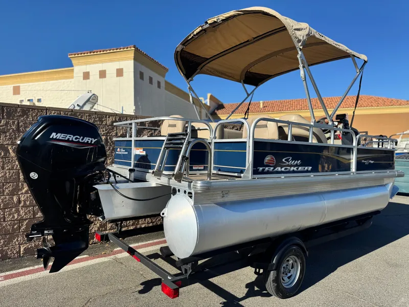 Slide: The Image of 2023 Sun Tracker Bass Buggy 18 DLX pontoon boat with Mercury engine, parked outdoors. - 6