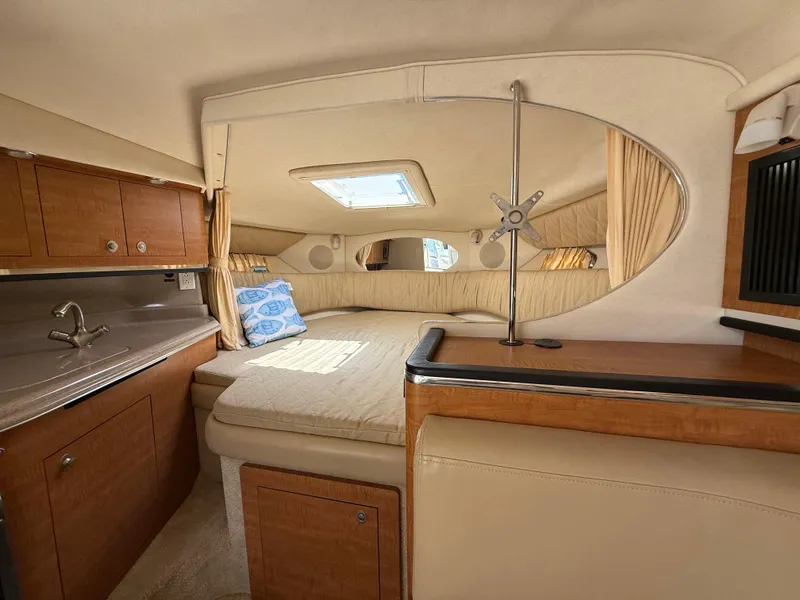 Slide: The Image of 2006 Sea Ray 290 Amberjack cabin interior with bed, sink, and wooden cabinetry. - 18