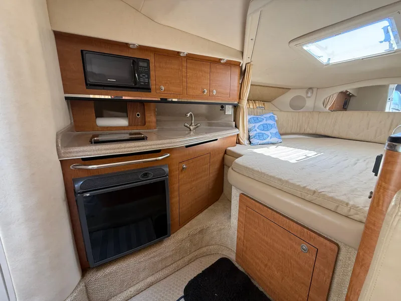 Slide: The Image of 2006 Sea Ray 290 Amberjack cabin interior with kitchenette and cozy sleeping area. - 19