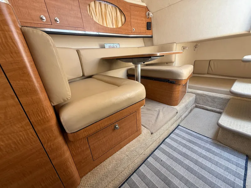Slide: The Image of 2006 Sea Ray 290 Amberjack cabin interior with beige seating and wooden accents. - 27