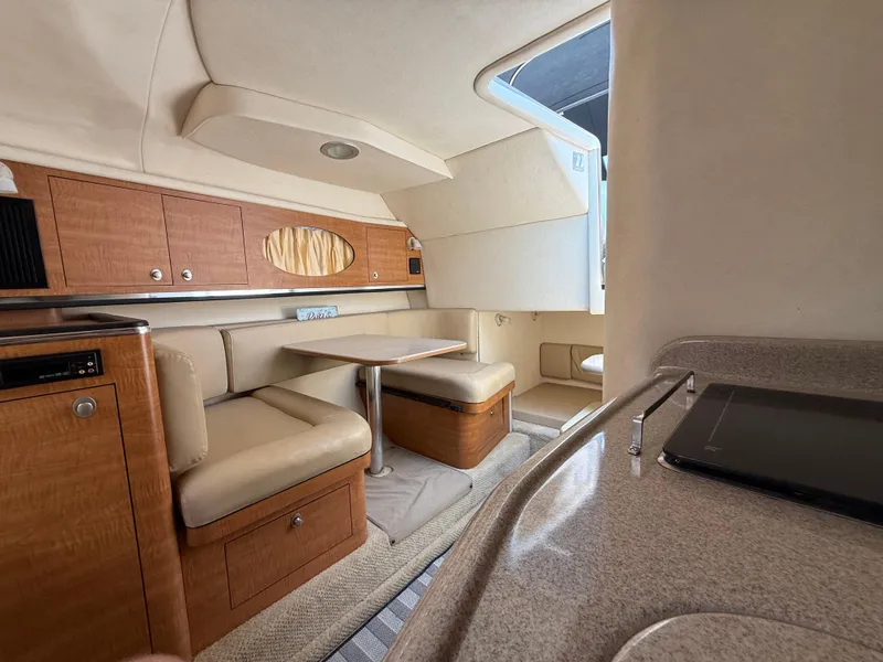Slide: The Image of 2006 Sea Ray 290 Amberjack cabin interior with seating, table, and wood cabinetry. - 28