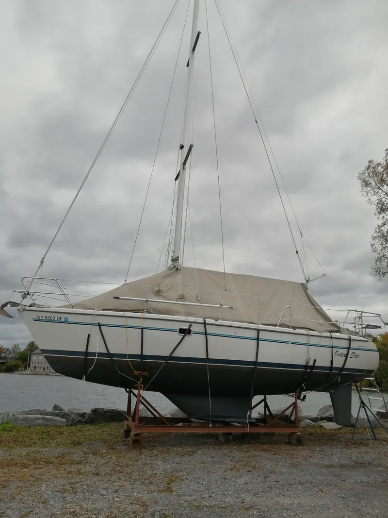 Slide: The Image of 1997 Catalina 28 MkII sailboat on land, covered, with overcast sky background. - 6