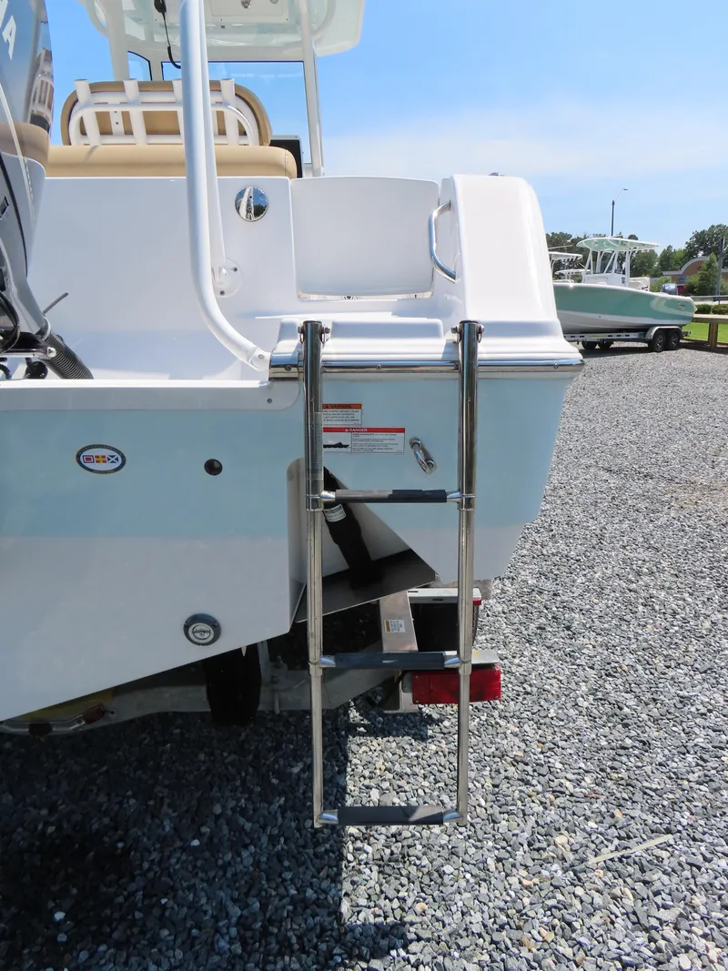 Slide: The Image of 2018 Sportsman Heritage 251 Center Console boat with rear ladder on gravel surface. - 6