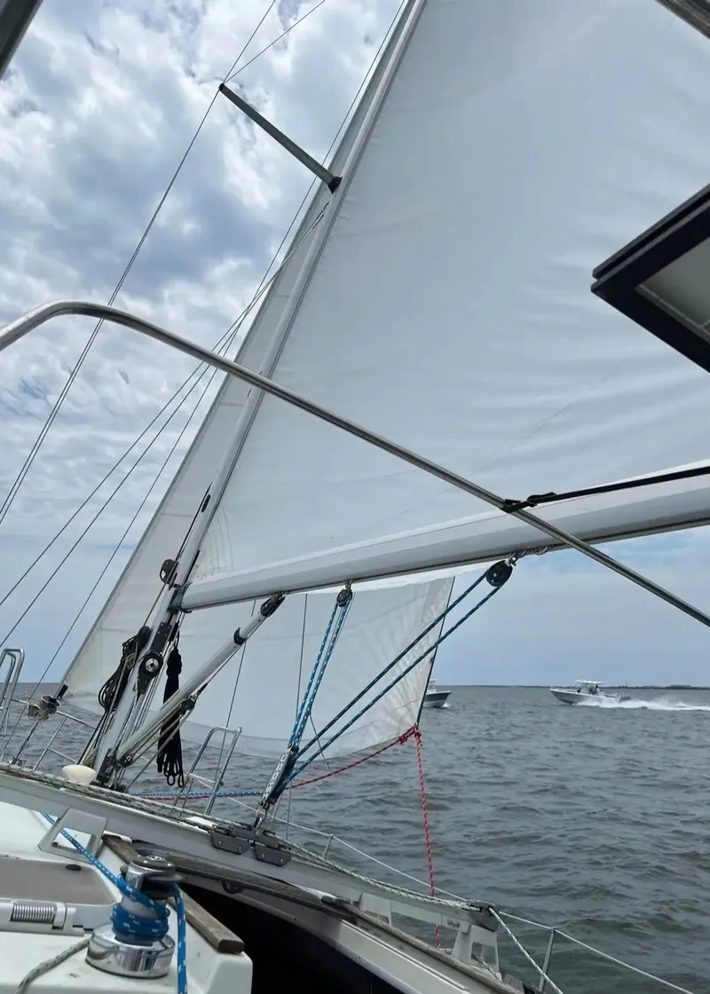 Slide: The Image of Sailing on a 1991 Beneteau MOORINGS 38 yacht with white sails against a cloudy sky. - 15