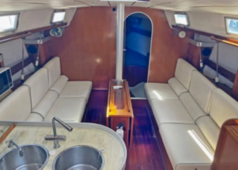 Slide: The Image of Interior of 1991 Beneteau MOORINGS 38 yacht with white seating and wooden finishes. - 3