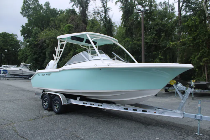 Slide: The Image of 2026 Key West 239 DFS boat on trailer, parked outdoors, surrounded by trees. - 3