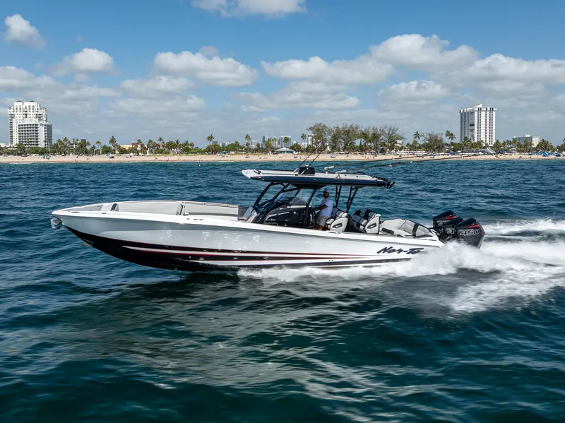 Slide: The Image of 2022 Nor-Tech 390 Sport Center Console boat cruising on ocean near city skyline. - 17