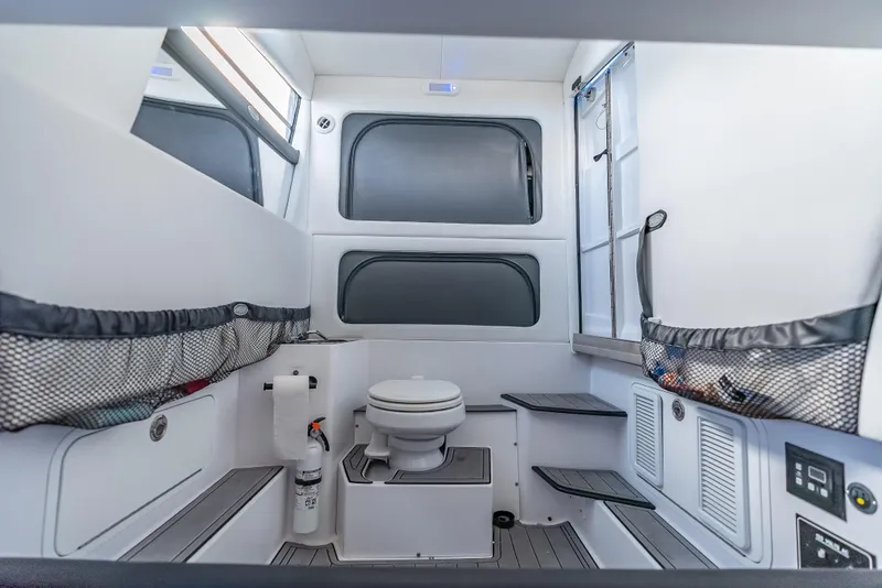 Slide: The Image of Interior of 2022 Nor-Tech 390 Sport Center Console boat, featuring a compact bathroom. - 48