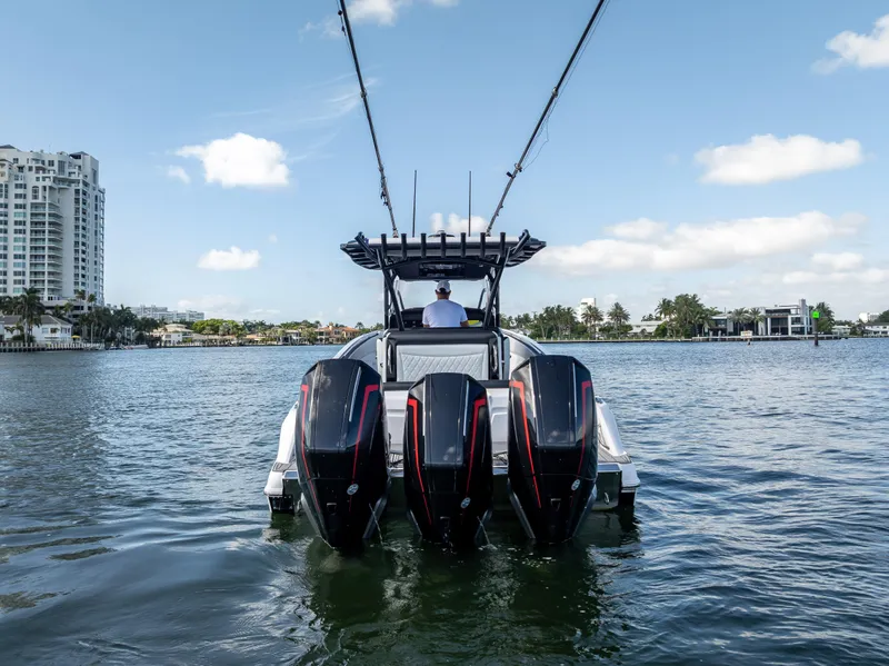 Slide: The Image of 2022 Nor-Tech 390 Sport Center Console boat on water, rear view with triple engines. - 9