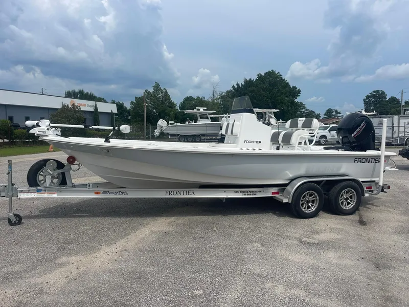 Slide: The Image of 2023 Frontier 2104 boat on trailer, parked outdoors under cloudy sky. - 2