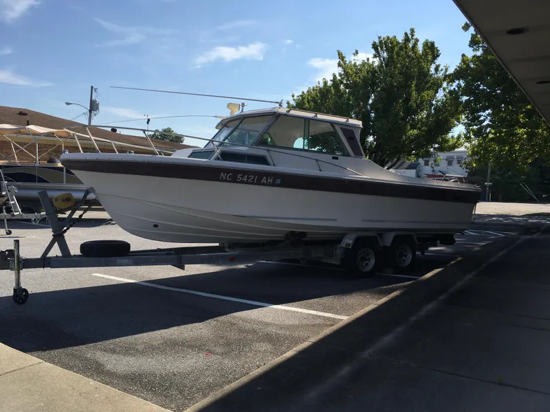 The Image of 1976 Sport-Craft 25 boat on trailer in parking lot, sunny day. - 1
