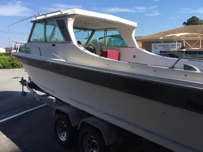 Slide: The Image of 1976 Sport-Craft 25 boat on trailer, parked outdoors under clear sky. - 2