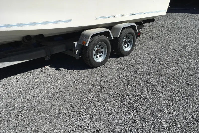 Slide: The Image of 1976 Sport-Craft 25 boat on a dual-axle trailer, parked on gravel. - 26