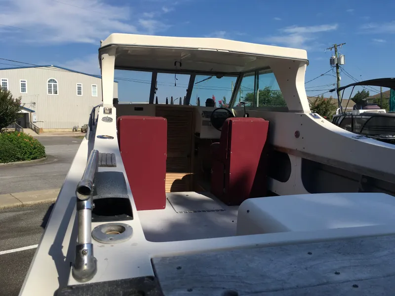Slide: The Image of 1976 Sport-Craft 25 boat interior with red seats and open cabin, parked outdoors. - 3