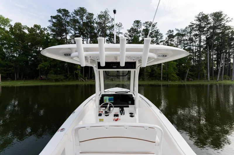 Slide: The Image of 2024 Sea Hunt Ultra 239 SE boat on a calm lake with forest background. - 17