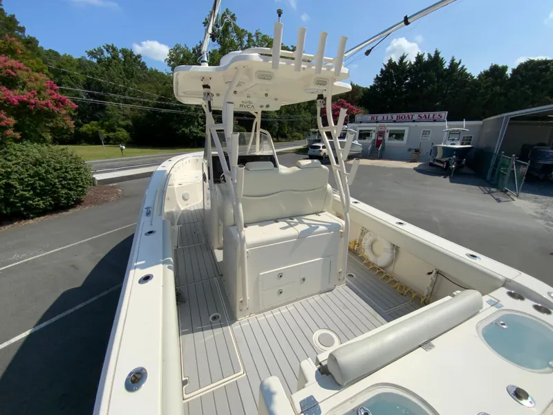 Slide: The Image of 2013 Cobia 296 Center Console boat at dealership, featuring spacious deck and seating. - 10