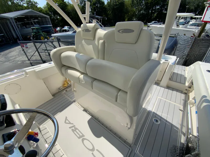 Slide: The Image of 2013 Cobia 296 Center Console boat with white seating and steering wheel, docked outdoors. - 13