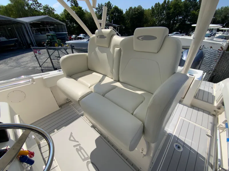 Slide: The Image of 2013 Cobia 296 Center Console boat with white cushioned seating in a marina setting. - 14