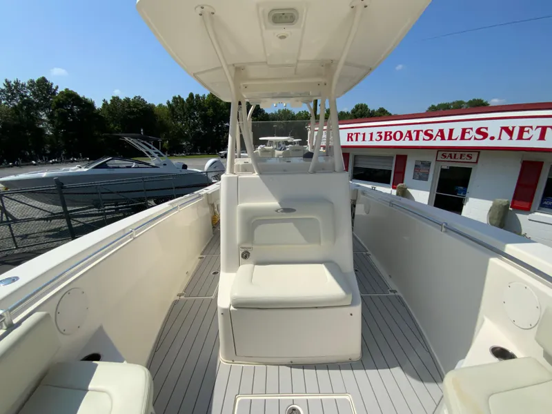 Slide: The Image of 2013 Cobia 296 Center Console boat at dealership, featuring spacious deck and seating. - 28