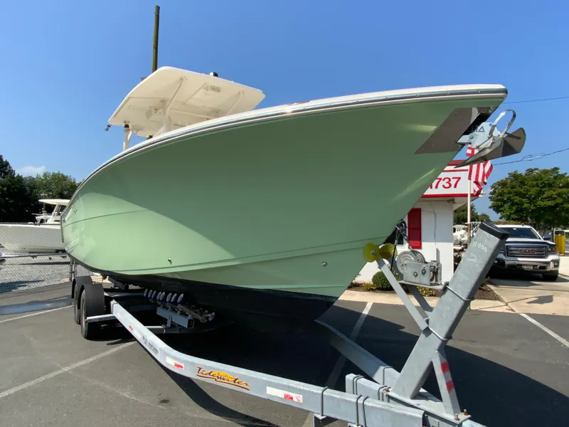 Slide: The Image of 2013 Cobia 296 Center Console boat on trailer, parked outdoors under clear blue sky. - 3