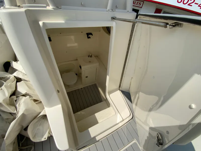 Slide: The Image of 2013 Cobia 296 Center Console boat interior with compact bathroom and storage area. - 31