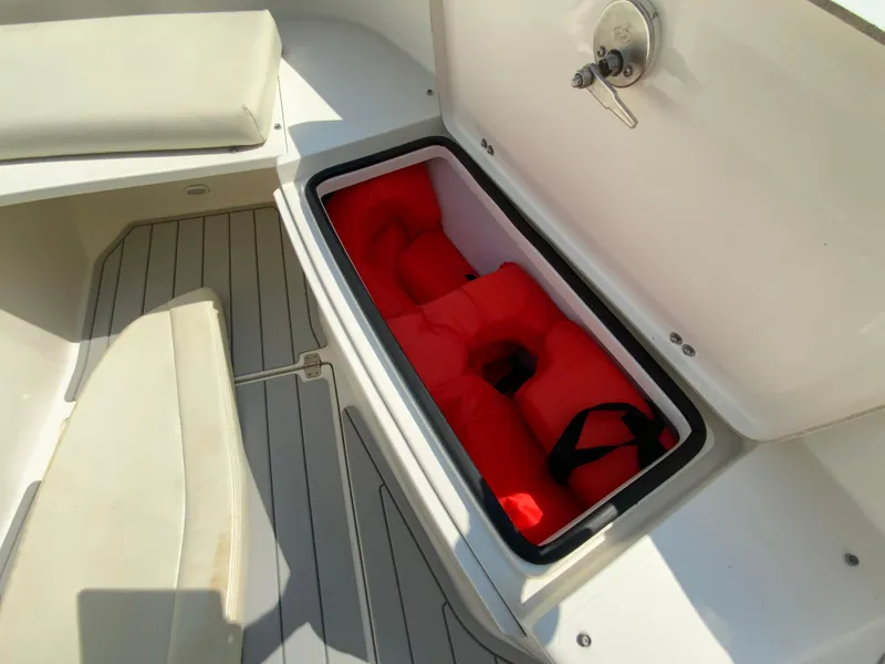 Slide: The Image of 2013 Cobia 296 Center Console boat with open storage compartment containing red life jackets. - 33